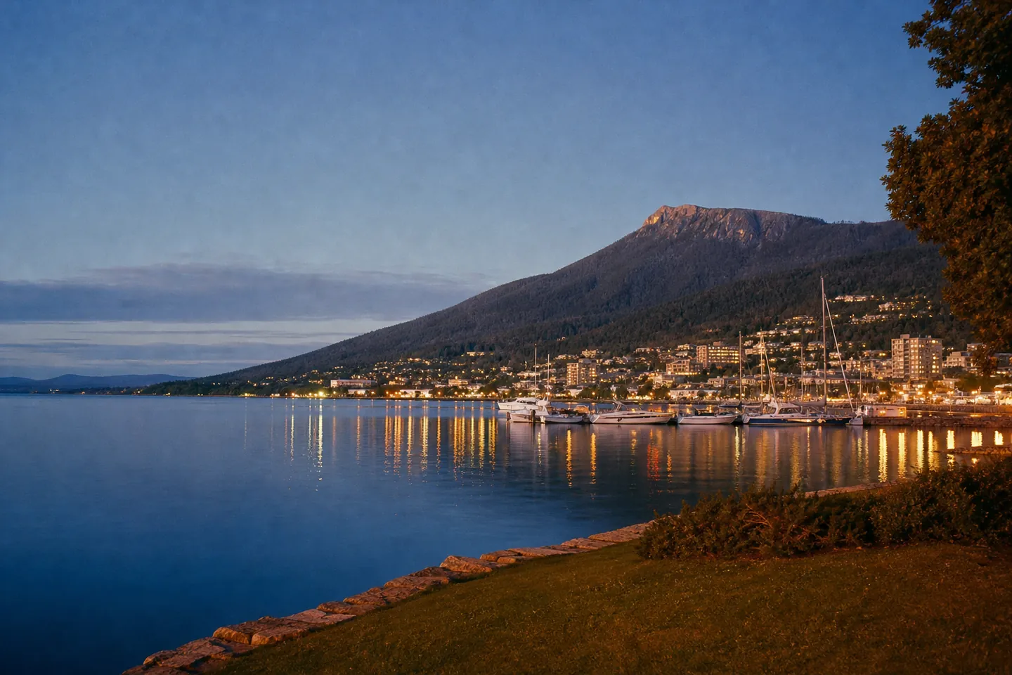 Illustration: a river estuary at blue hour with a mountain behind a small lit city and moored yachts